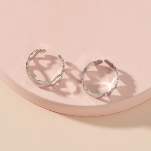 Close-up of two silver minimalist open toe rings with hollow heart patterns on a display