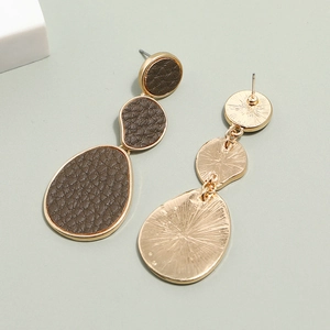 Detail of long drop earrings featuring gold alloy and brown lychee textured leather inserts