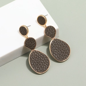 Detail of long geometric earrings with dark brown lychee leather and gold metal edging