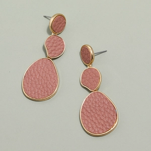 Close-up of pink lychee grain leather inlays and gold metal frames on drop earrings