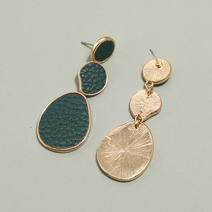 Detail showing irregular geometric gold earrings with dark green textured leather inlay