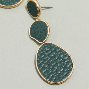 Macro view of long drop earrings with green lychee leather and gold pebble frames