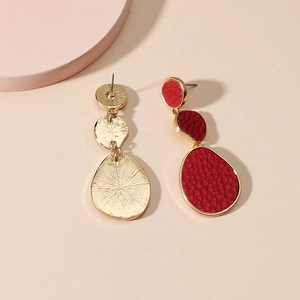 Detail of red textured leather earrings with triple layered gold brushed metal backings
