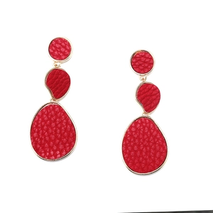 Detail view of long geometric earrings with red leather texture and gold metal frames