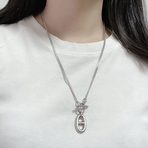 Collana a maglia marina argentata con chiusura a T indossata su sfondo bianco