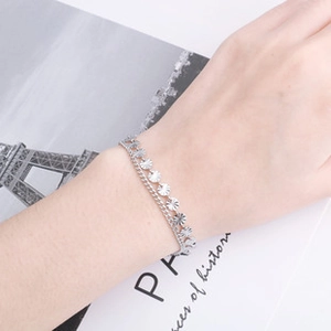 Dettaglio di un bracciale a strati in acciaio inossidabile con ciondoli a raggiera al polso