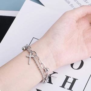 Dettaglio del bracciale multistrato in acciaio inossidabile con croce e catena a graffetta
