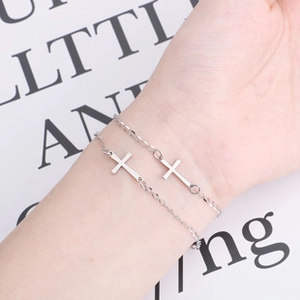 Dettaglio di due braccialetti minimalisti con croce in acciaio inossidabile argento