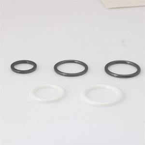 Juego minimalista de cinco anillos de cerámica pulida en blanco y negro sobre fondo blanco