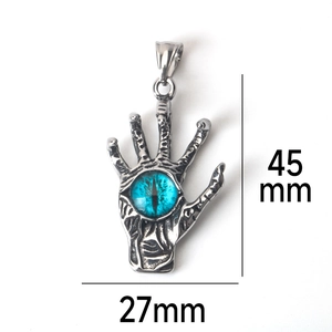 Detalle de colgante mano gótica con ojo de diablo azul y textura de acero inoxidable