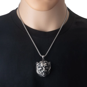 Colgante de cabeza de león de acero inoxidable pulido sobre una camiseta negra de hombre