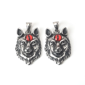 Detalle de dos colgantes de cabeza de lobo con ojos de piedra roja y estilo punk