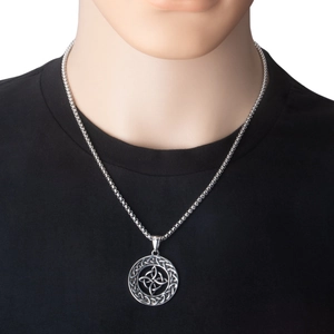 Close-up of a vintage stainless steel Celtic knot pendant necklace on a black shirt backdrop