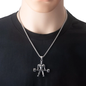 Nahaufnahme eines silbernen Hantel-Anhängers bei einem Mann im schwarzen T-Shirt
