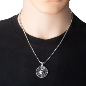 Gros plan d'un pendentif Yin Yang vintage sur une chaîne en argent et t-shirt noir