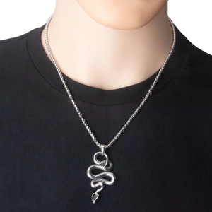 Gros plan d'un pendentif serpent en acier inoxydable argenté sur un t-shirt noir uni