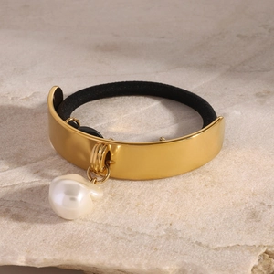 Élastique à cheveux doré avec pendentif perle baroque sur une surface en marbre