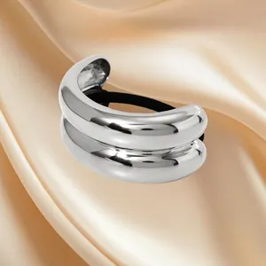 Polished silver stainless steel ponytail cuff with black elastic band on silk background