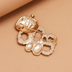 Golden enamel pumpkin brooch showing detailed metal texture and safety pin clasp