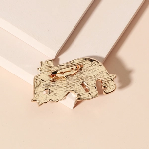 Golden retro polar bear enamel brooch with bow tie on a minimalist beige background
