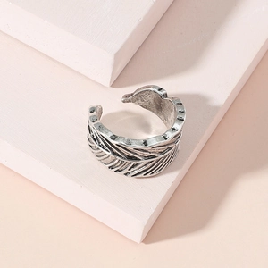 Anillo de pluma plateado vintage ajustable sobre un bloque geométrico rosa elegante