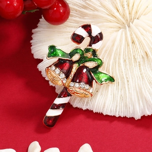 Broche de Noël canne de bonbi avec cloches rouges et nœud vert sur fond rouge