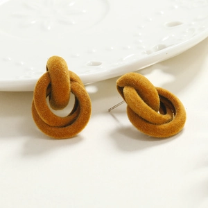 Macro shot of mustard yellow flocked interlocking geometric stud earrings on a ceramic dish