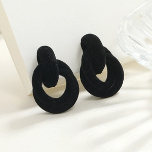 Detailed close-up of double interlocking black flocked earrings with a matte velvet finish