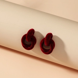 Detail of red interlocking velvet earrings with elegant flocked texture on round props