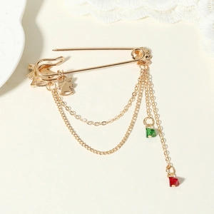 Christmas gold brooch with jingling bells, tassels and colorful crystals on lace background