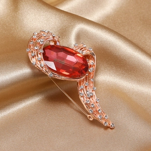Close-up of vintage rose gold brooch with a large red oval gemstone and pavé diamonds