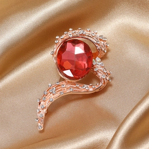 Detailed close-up of a rose gold heart brooch with a large red stone and white rhinestones