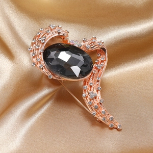 Detailed macro view of an elegant rose gold brooch with black gemstone on silk