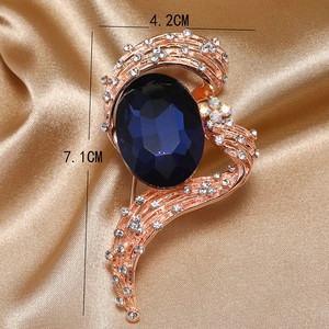 Detailed macro view showing a 7.1cm tall vintage brooch with deep blue gem and rhinestones