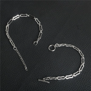 Dettaglio di bracciali a catena argentata con chiusura a moschettone e OT su pelle nera
