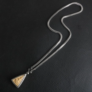 Macro view of silver stainless steel chain with a golden Buddha pendant on black leather