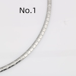 Dettaglio macro della collana piatta a serpente in acciaio con trama a rombi sbalzati