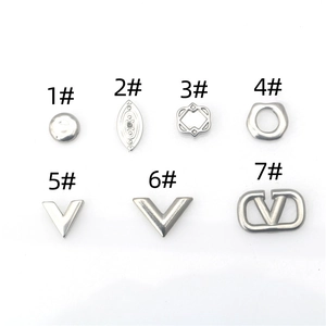 Détail de pendentifs géométriques argentés avec breloques en métal en cercle, losange et V