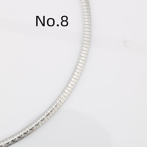 Dettaglio macro della collana a catena piatta color argento con incisione a spina di pesce