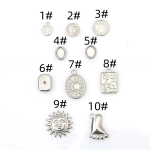 Flat lay of ten diverse stainless steel hip-hop charms including sun and coin relief shapes
