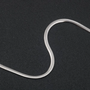 Macro shot of silver flat snake chain texture with polished reflective metal surface