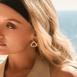 Minimalist gold triangle hoop earrings in titanium steel worn by model in sunlight