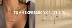 Détail de colliers en acier titane doré avec pendentifs en forme de cœur et émeraude