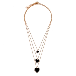 Close-up of triple-layered gold necklaces with black heart pendants and crystal edges