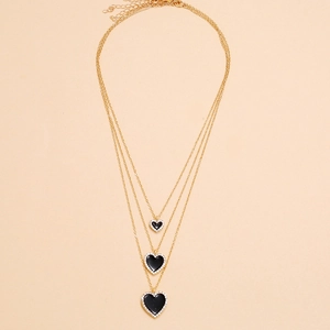 Detailed view of layered gold necklace featuring three black crystal heart pendants