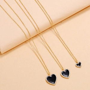 Detailed view of layered gold heart necklaces with black enamel and white zircon stones