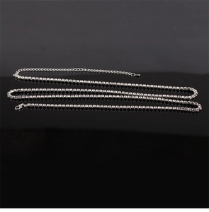 Detailed shot of silver rhinestone body chain with lobster clasp on reflective black surface