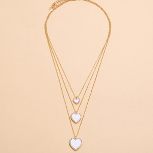 Detail of gold layered necklaces with white enamel heart pendants and pavé zircon edges
