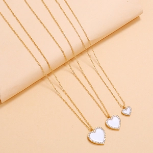Close-up of golden layered heart necklaces with white enamel and sparkling rhinestones