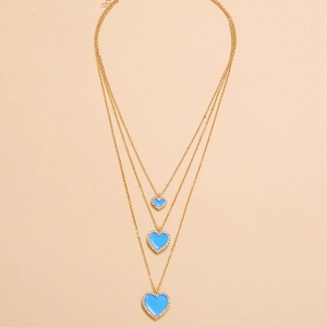 Detailed view of triple-layered gold necklaces with blue rhinestone heart pendants